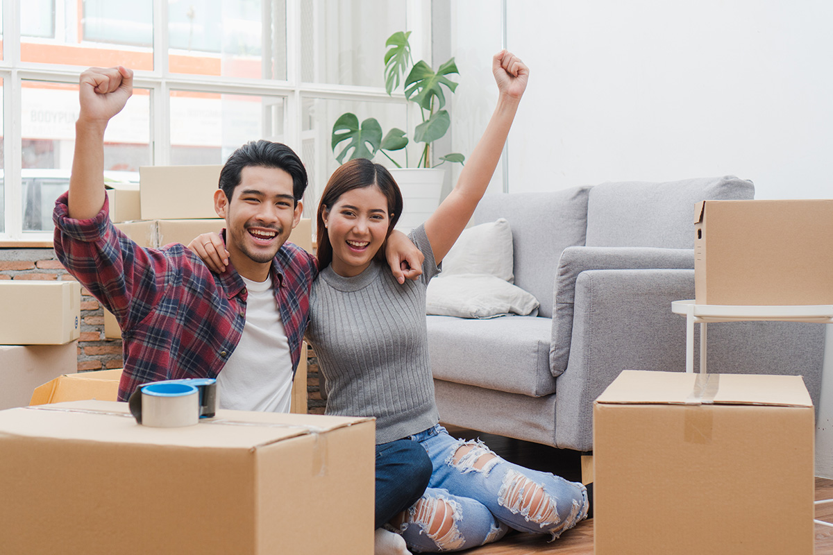 new house / home moving and relocation concept. Happy asian new married couple looking at each other face after moving in new apartment and start new life together.